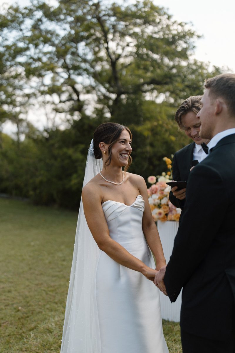 Bride smiling with her bouquet during the vows