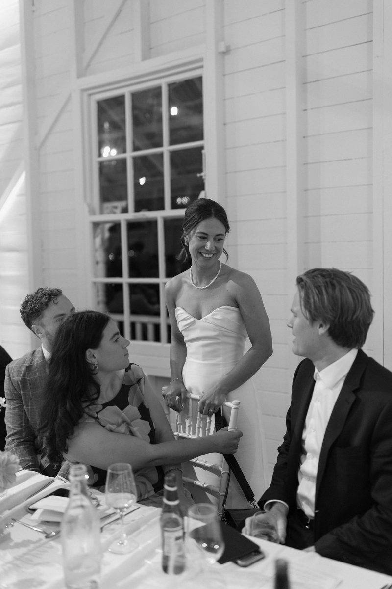 Bride and groom greeting seated guests at the reception, in black and white