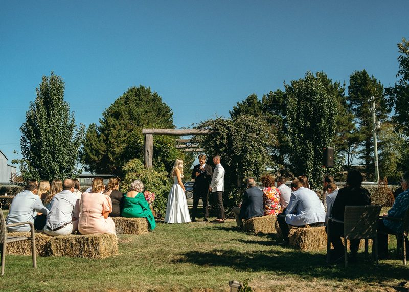 Farm ceremony with guests seated on hay bales