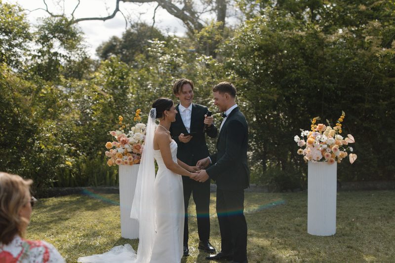 Brayden Wedd marrying a couple at a garden ceremony between floral plinths